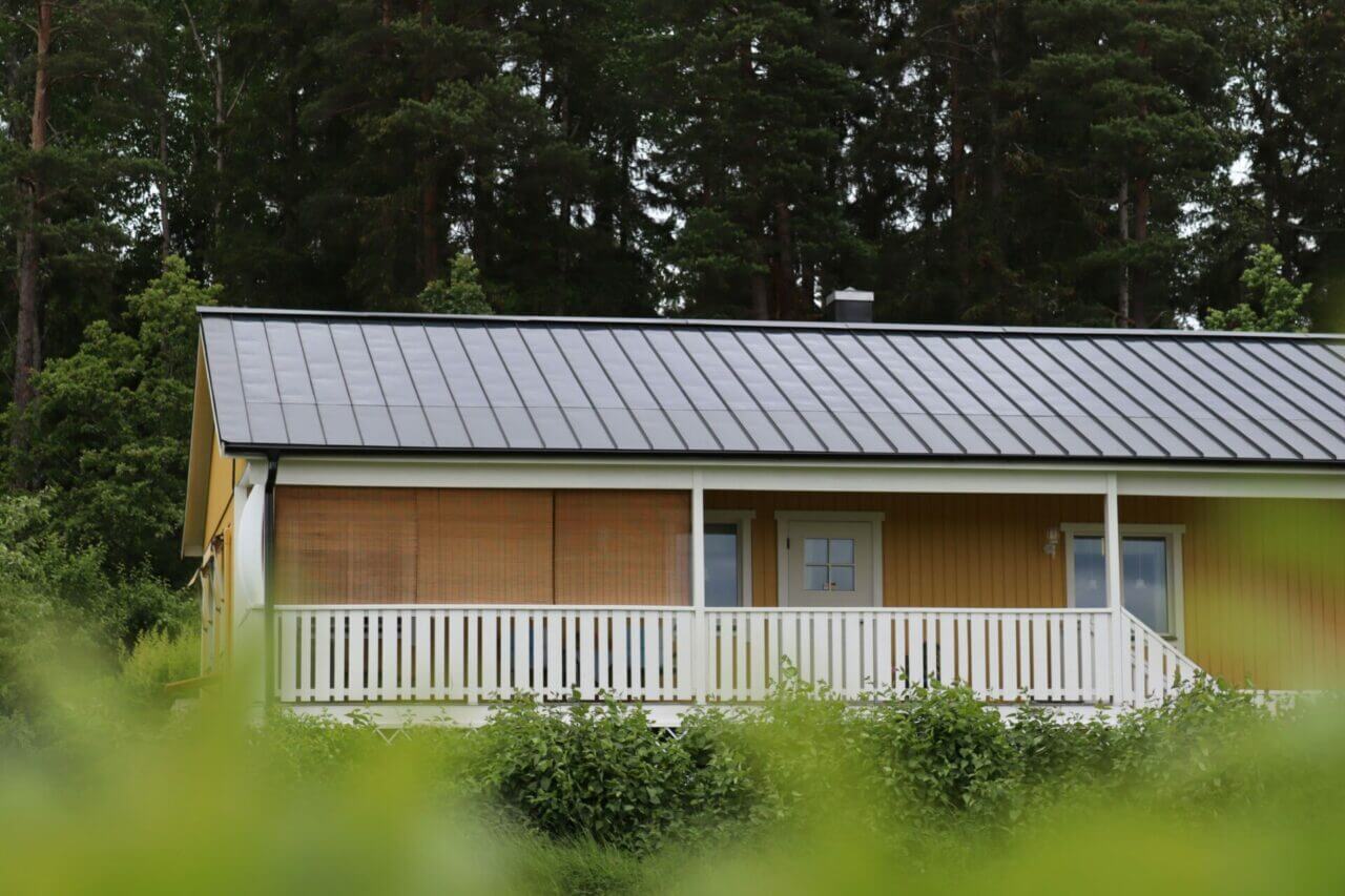 Halvbild av ett gult hus med slim solceller på taket